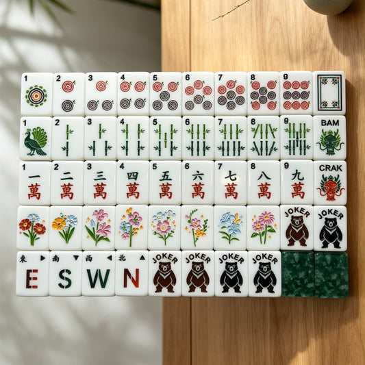 Top-down view of neatly stacked Forest Fern mahjong tiles on wooden table, showing complete custom artwork: bear jokers, peacock bamboo, floral season tiles, wind and dragon symbols