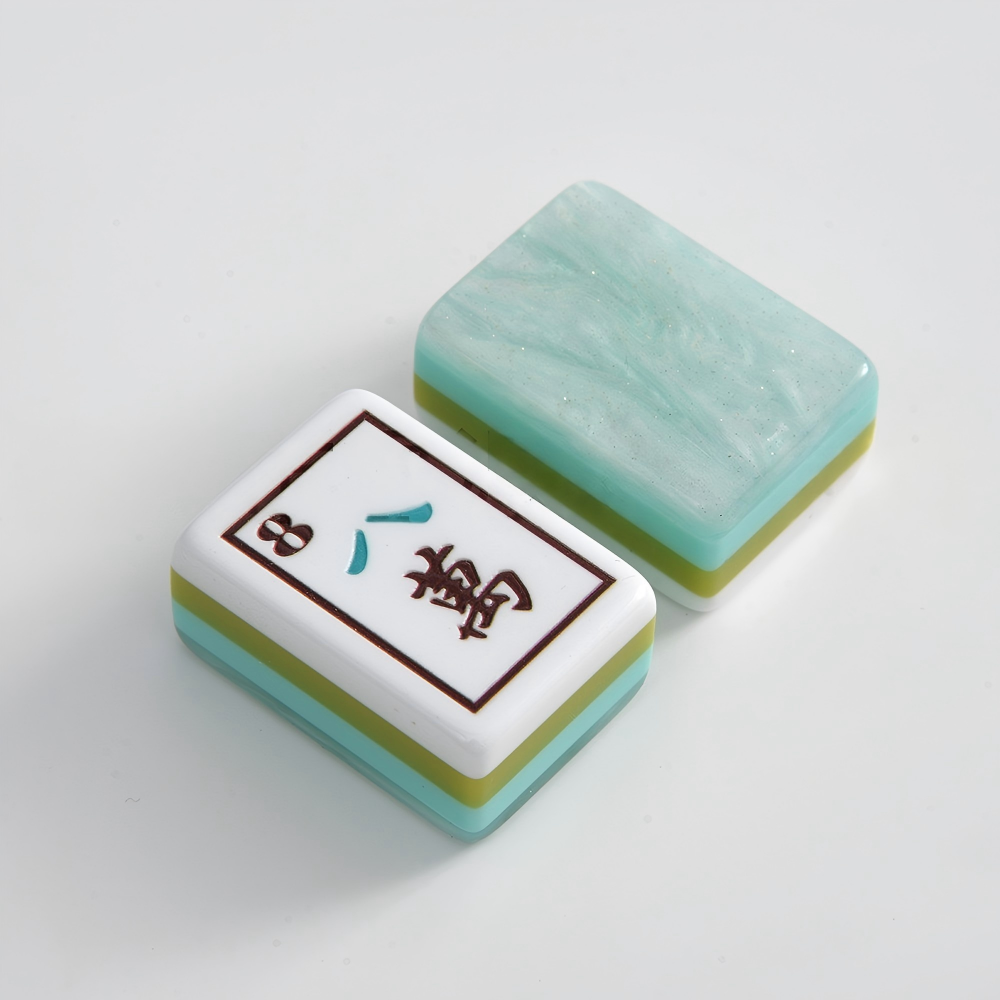 A breath of fresh sea air for your mahjong table. The Coastal Mist features soft mint-marbled acrylic backs with signature multi-layer side stripes in turquoise, lime, and white paired with crisp white faces and exclusive ocean-themed Joker and Flower illustrations. It's coastal elegance meets full NMJL tournament functionality.