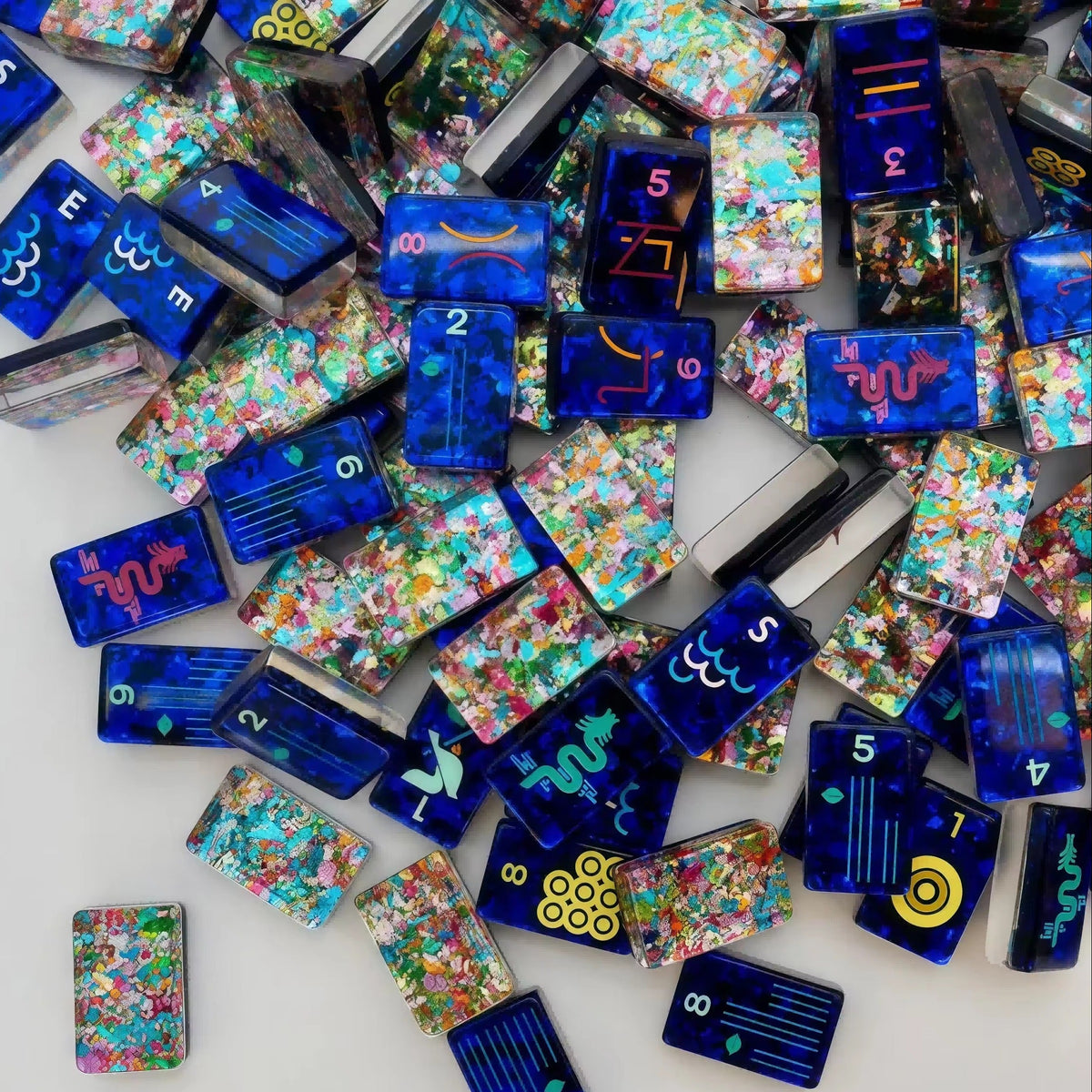 Scattered Confetti Sapphire American mahjong tiles on white background, deep blue resin tiles with embedded rainbow confetti flakes and bright neon pop art graphics