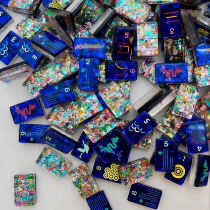 Scattered Confetti Sapphire American mahjong tiles on white background, deep blue resin tiles with embedded rainbow confetti flakes and bright neon pop art graphics