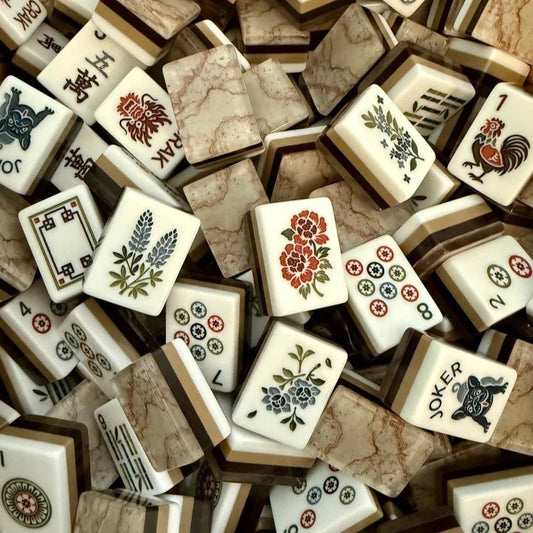 Flat lay of Pink Marble Floral American mahjong tiles arranged neatly on clean white background, white tile fronts with green floral dot patterns, classic bamboo, red dragons, multi-color flower tiles and crown jokers