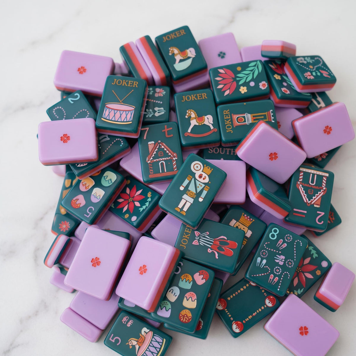 The most magical mahjong set of the season.The Holiday Nutcracker is a limited-edition collector's piece featuring rich evergreen melamine tiles adorned with hand-illustrated Christmas art from the iconic nutcracker soldier Jokers and pink ballet slipper Jokers to gingerbread house Craks, frosted cake Dots, ballerina winds (NEWS), poinsettia flowers, Christmas trees, and grandfather clocks. The ultimate holiday gift for the American Mahjong lover in your life.