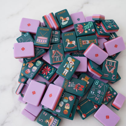 The most magical mahjong set of the season.The Holiday Nutcracker is a limited-edition collector's piece featuring rich evergreen melamine tiles adorned with hand-illustrated Christmas art from the iconic nutcracker soldier Jokers and pink ballet slipper Jokers to gingerbread house Craks, frosted cake Dots, ballerina winds (NEWS), poinsettia flowers, Christmas trees, and grandfather clocks. The ultimate holiday gift for the American Mahjong lover in your life.