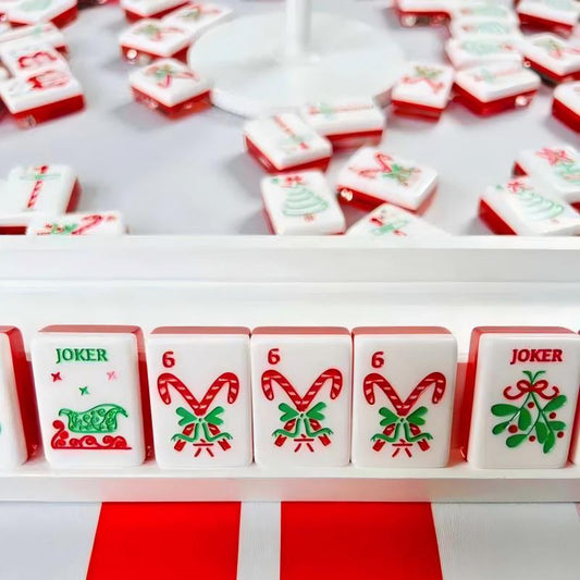 Christmas Cheer mahjong tile rack close‑up, sleigh joker tile, candy cane suit tiles, mistletoe joker, glossy solid red tile backs, festive holiday custom American mahjong tiles