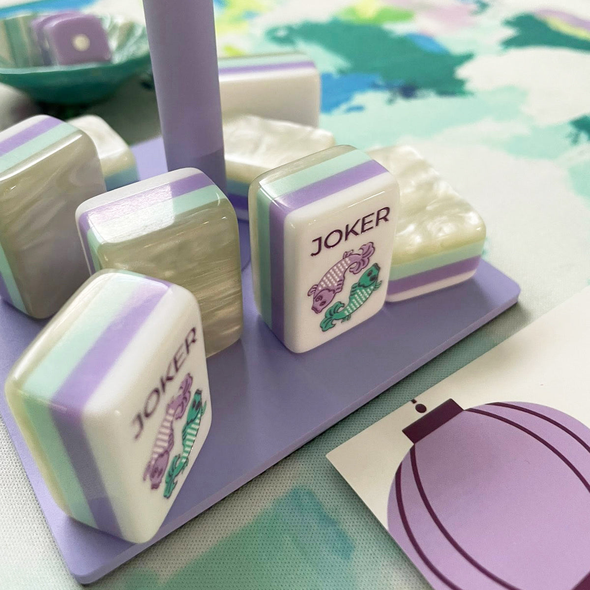 Close-up of koi fish joker mahjong tiles on purple acrylic rack, layered pastel mint and lavender tile sides, colorful koi artwork on white tile faces