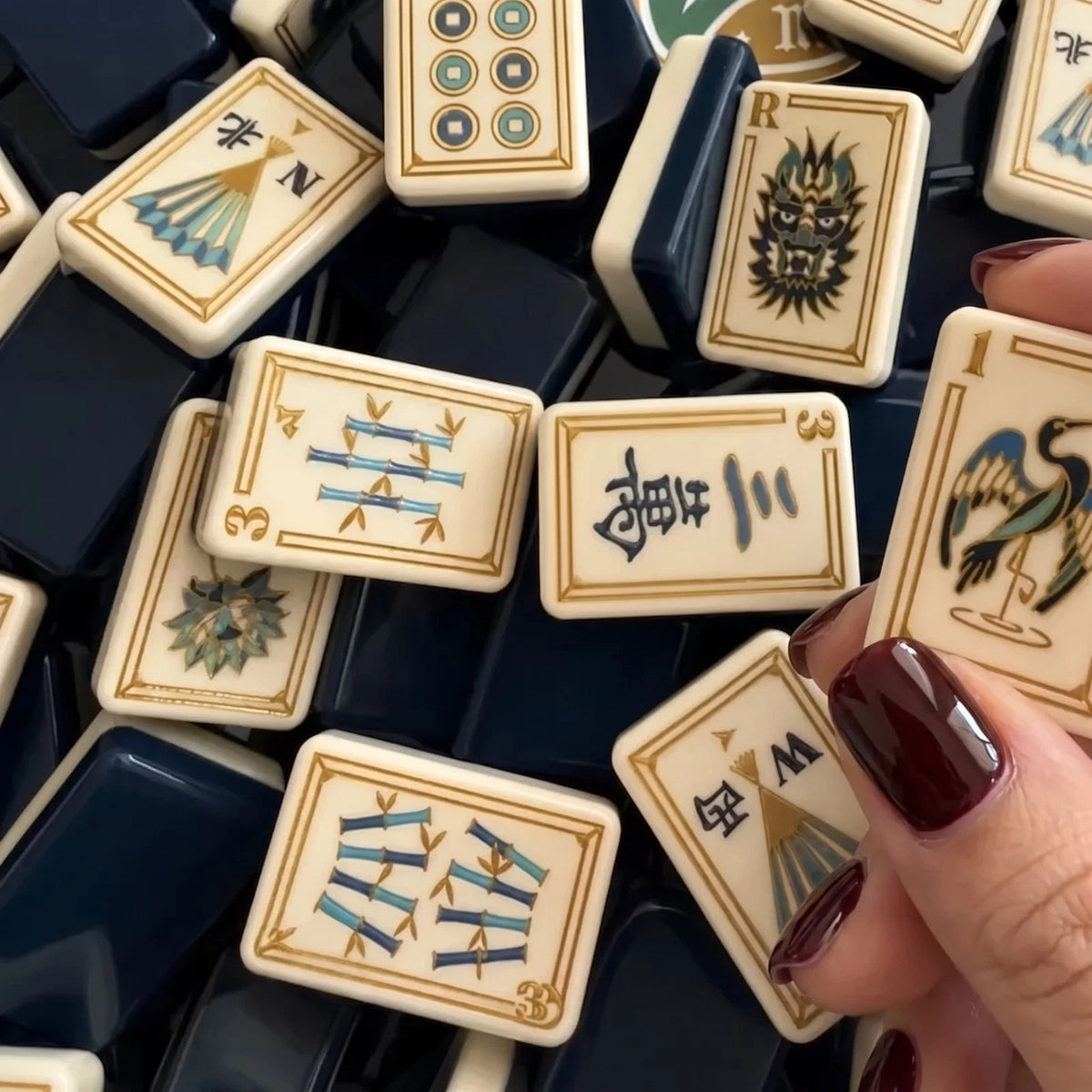 Evoking timeless oriental elegance, this Imperial Navy American mahjong set features luxe gold‑bordered cream tile faces decorated with classic East‑Asian wildlife and botanical art. Graceful cranes, symbolic turtle jokers, fierce dragon motifs, lush lotus florals, coin‑styled dot tiles and ornate fan‑shaped wind tiles elevate every suit. Rich deep navy‑blue high‑gloss tile backs deliver a premium, sophisticated finished look.