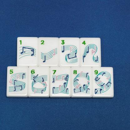 Flat lay of 1-9 dot suit mahjong tiles, white tiles printed with colorful swirling music note artwork on dark blue background