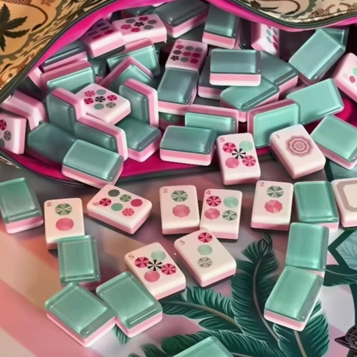 Tropical Floral mahjong tiles spilling from printed tropical fabric carry pouch onto palm leaf game mat