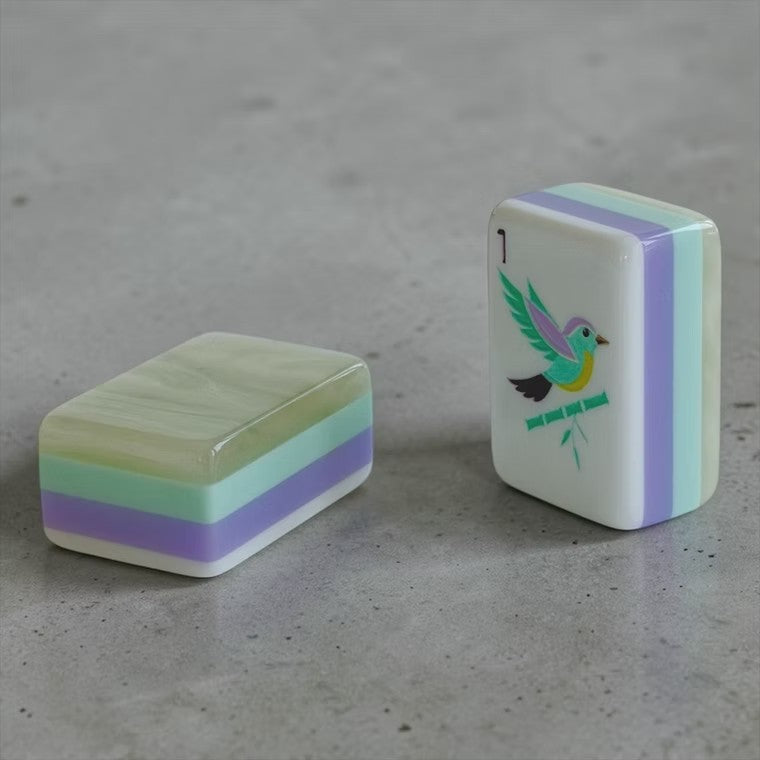 American mahjong tiles arranged on clear acrylic rack on pastel floral game mat, showing N/E/W/S fan wind tiles, bamboo and dot suits