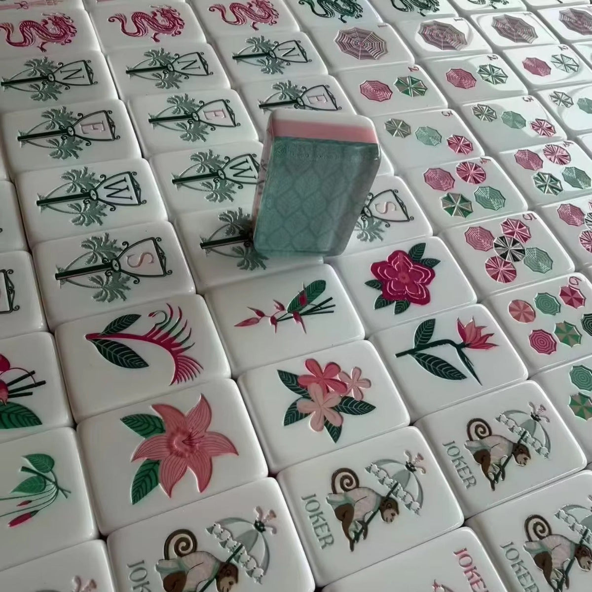 Tropical Floral mahjong tiles spilling from printed tropical fabric carry pouch onto palm leaf game mat