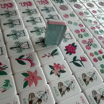 Tropical Floral mahjong tiles spilling from printed tropical fabric carry pouch onto palm leaf game mat