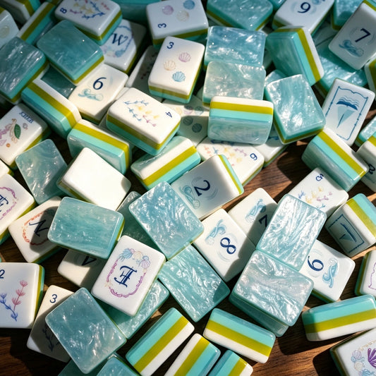 Flat top-down view of fully arranged Ocean Tide American mahjong tiles, custom nautical artwork including seashells, seaweed, sailboat and sea creature jokers, turquoise pearlescent tile backs with green-blue layered side stripes on clean white background