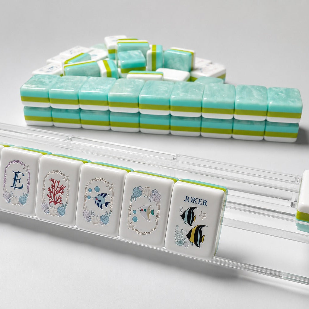 Product dimension shot of Ocean Tide mahjong tile, showing front seashell graphic and side tri-color stripe, marked with tile size measurements on sunlit wooden table