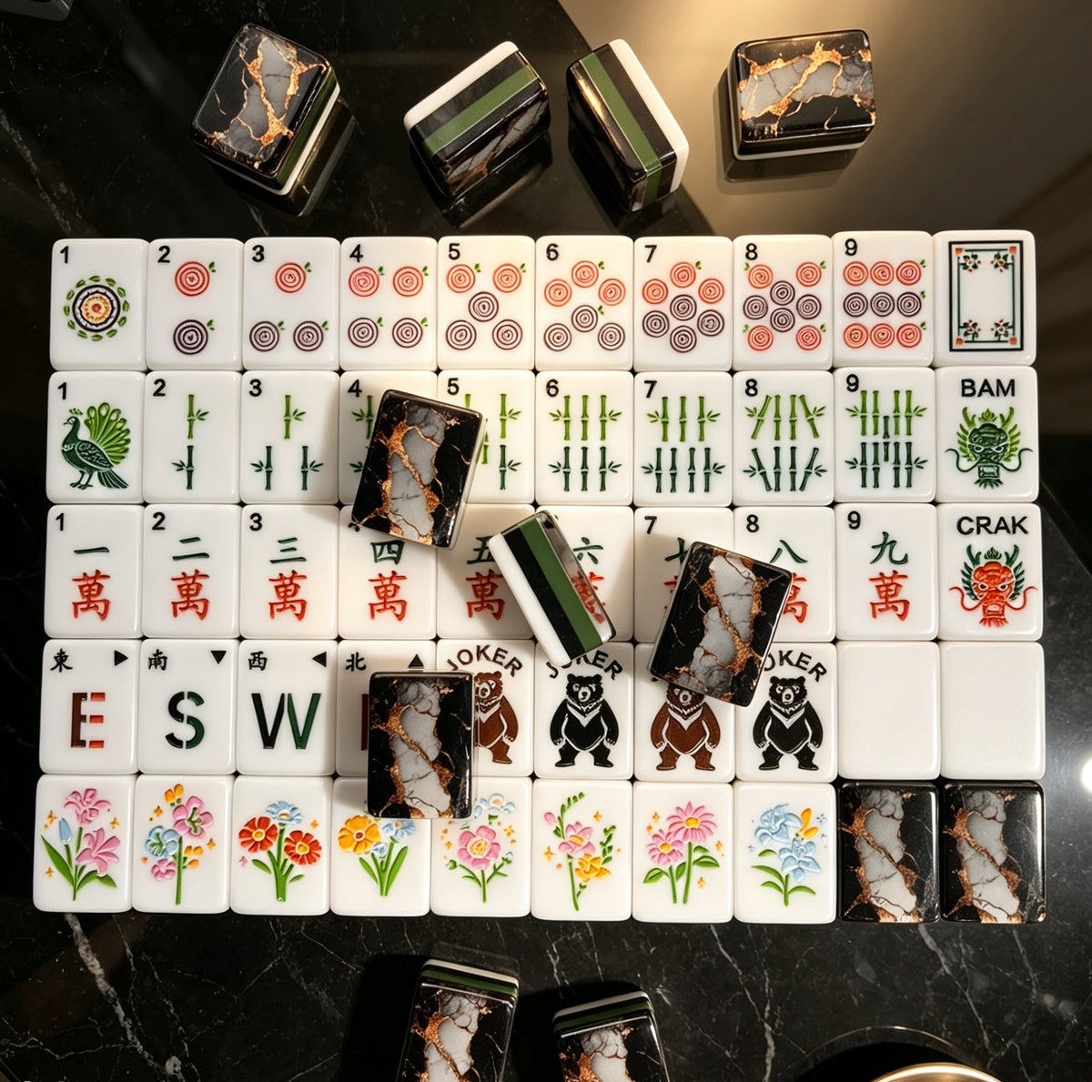 Overhead shot of scattered black gold marble mahjong tiles on gold tray, luxury black marble with gold foil backs, green striped edges, peacock tile and classic mahjong suit illustrations