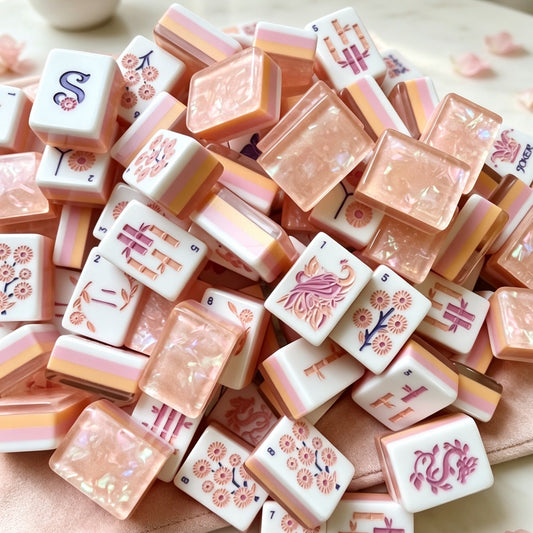 Scattered Orchid Crown Pink American mahjong tiles flat lay, white tiles with rose gold daisy, phoenix and dragon artwork, shimmer blush pearlescent backs, marble table with cherry blossom petals
