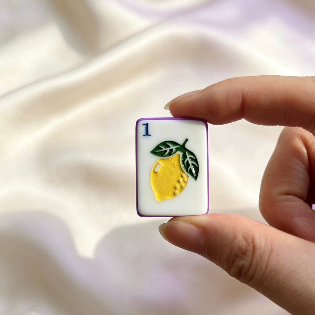 Overhead shot of scattered Purple Rainbow Striped mahjong tiles, rainbow striped side edges, fruit and botanical illustrations, styled on wooden table with purple paper decor