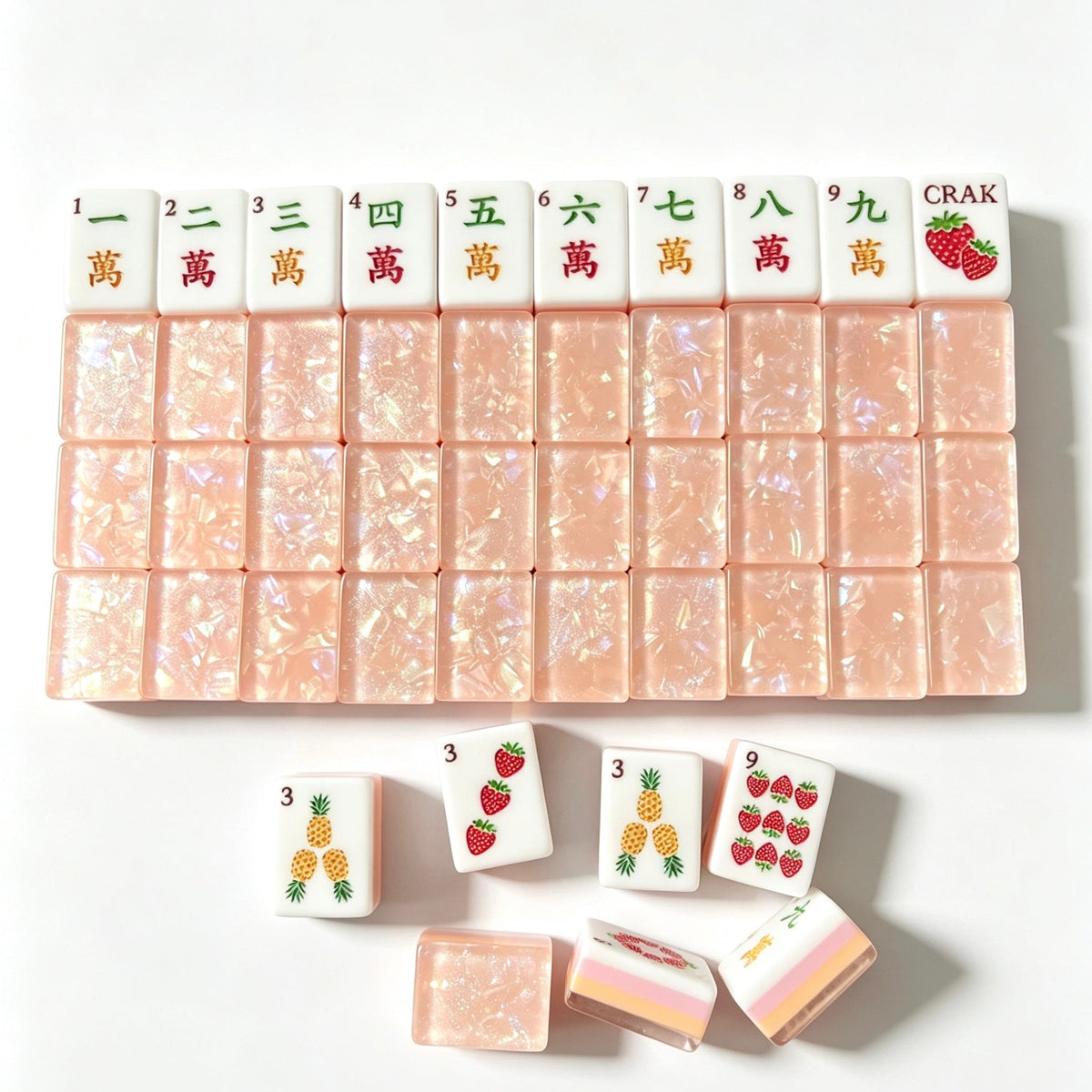 Tropical Fruit Garden American mahjong tiles scattered on marble table, pink shimmer crushed shell backs, pastel layered side stripes, strawberry and pineapple fruit illustrations, cream silk fabric backdrop