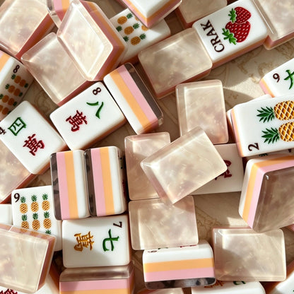 Flat lay view of neatly arranged Fruit Garden American mahjong tiles, custom fruit artwork: strawberry crak, pineapple bam, fruit basket jokers and botanical flower illustrations on vintage paper background