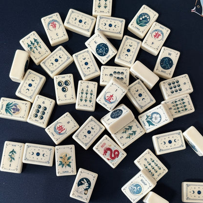 Side view of Moon Rabbit Tarot mahjong tiles lined up on acrylic rack over dark navy velvet fabric, cream ivory tiles with tarot border design, moon & star dots, floral bams, Chinese character cracks and moon rabbit lantern joker tile