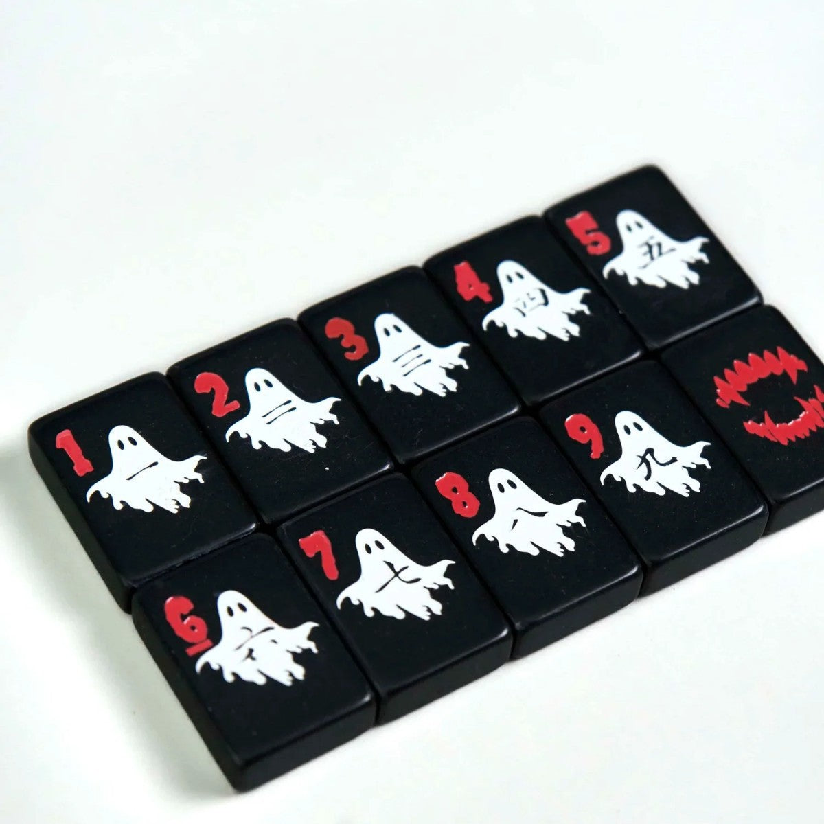 Spooky Hallow mahjong overhead flat‑lay on white background, full Halloween themed tile assortment, ghost, pumpkin, skull and spooky joker tiles, black base American mahjong pieces